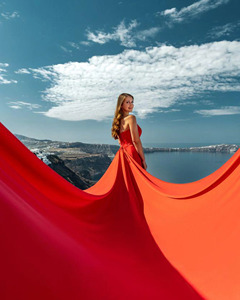 Impresionante sesión de fotos en Santorini con una elegante mujer en un vestido rojo vibrante sin espalda y con una cola larga y fluida. - Product Image 3