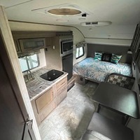Caravane compacte avec lit, cuisine, coin repas et climatiseur, idéale pour le camping et les voyages en voiture