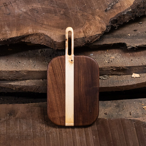 Superbe planche à découper en bois de noyer, présentant un design rayé contrastant en bois clair et foncé avec une poignée intégrée. - Product Image 1
