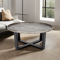 Table basse élégante en aluminium et fer, finition argentée antique, support de conception croisée à dessus rond pour une utilisation en intérieur