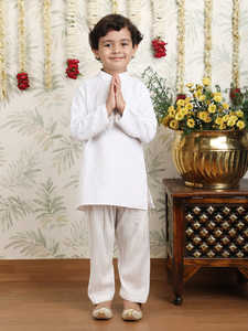Niño con kurta y pijama blancos en pose de pie lateral, sonriendo, fondo festivo, decoración floral, elegante, tradicional, retrato infantil - Product Image 3