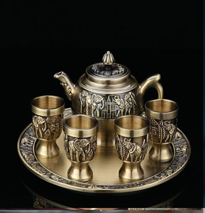 Juego de té vintage de latón con detallados relieves de elefantes en una bandeja redonda de metal. Disponible a precios de mayorista. - Product Image 1