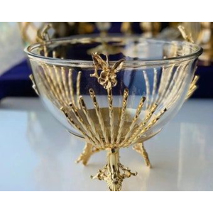Tazón de lujo para servir alimentos y dulces, hecho de vidrio transparente en forma redonda, con base de metal chapado en oro y un diseño único. - Product Image 1