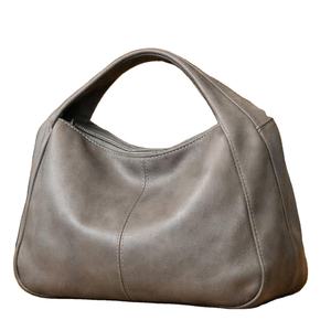 Este artículo es un bolso de hombro estilo hobo de cuero gris, similar a los bolsos hobo de cuero vegano de DOURR o Bokzim. - Product Image 1