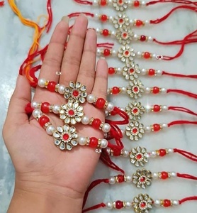 รากีดีไซน์เนอร์ระดับพรีเมียมประดับด้วยคุนดันและไข่มุกสำหรับพี่ชาย  แบบดั้งเดิมลายดอกไม้สีแดงและสีขาว  พร้อมด้วยด้ายมีนาคารี  สำหรับเทศกาลรักชาบันธัน - Product Image 1