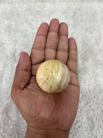 Bola batu akik Crazy Lace dengan pola bergelombang berwarna oranye krem dan abu-abu yang rumit, berbentuk bulat yang dipoles, dan unik.