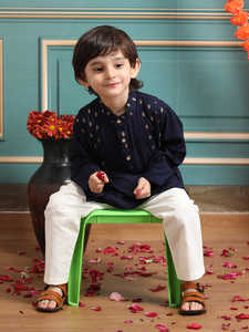 Adorable niño con kurta y pijama tradicionales, de pie con pétalos de flores, en un ambiente festivo de estudio interior con pared decorativa. - Product Image 6