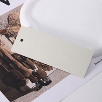 Étiquette suspendue en papier coton blanc avec logo gaufré et pelliculage UV, accessoires vestimentaires personnalisés, vente en gros de mode