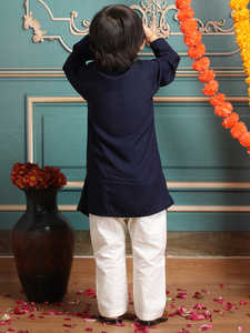 Adorable niño con kurta y pijama tradicionales, de pie con pétalos de flores, en un ambiente festivo de estudio interior con pared decorativa. - Product Image 2