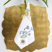 Lino natural con bordado de aciano, suave pero duradero, con vibrantes flores azules que añaden un toque fresco y elegante a las mesas.