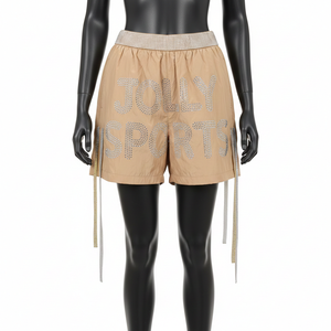 Shorts cortavientos de alta calidad para mujer, en nailon suave GSM, color beige arena, con logotipo de transferencia térmica con pedrería. - Product Image 1