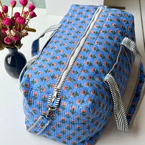Sac de voyage matelassé bleu à motifs floraux avec poignées rayées, fermeture éclair, design portable pour un usage décontracté en voyage - Product Image 1
