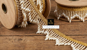 Encaje de lujo con ribete trenzado en zig-zag color crema dorado, con borlas de perlas vibrantes y flecos de cuentas grandes para diseños de lehenga y vestidos de lujo. - Product Image 1