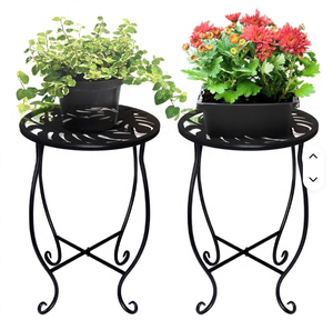 Support décoratif pour plantes en métal noir avec plateau rond découpé en forme de feuille, pieds courbés et base en X robuste, idéal pour les fleurs - Product Image 1