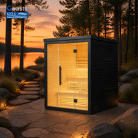 Sauna de jardin Sunset avec toit plat, finition en planches foncées et intérieur en bois naturel pour une escapade en bord de lac