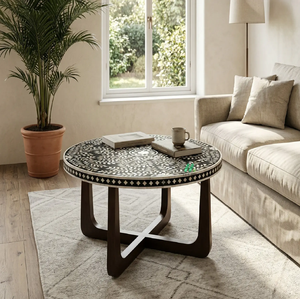 Mesa de centro redonda con incrustaciones de hueso negro que exhibe delicados motivos de hojas de vid blancas sobre una base de madera oscura con patas cruzadas. A precio de mayorista. - Product Image 1