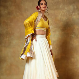 ชุดเลเฮนกาโชลีสีงาช้างสุดหรู พร้อมผ้าคลุมไหล่สีเหลืองมัสตาร์ดและขอบผ้าปักดิ้นเงิน |   ชุดงานแต่งงานสุดหรูสไตล์ชาติพันธุ์สำหรับผู้หญิง - Product Image 1