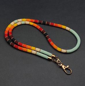 Cadena corporal hecha a mano con cuentas y cierre dorado, con diseño de rayas en azul claro, crema, amarillo, naranja, rojo, granate y negro. - Product Image 1
