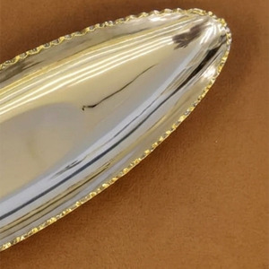 Ce plateau élégant finition argentée présente un design ovale pointu et une bordure dorée détaillée, offrant un luxe pour le service et la décoration. - Product Image 3