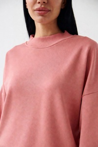 Joven mujer elegante en una sudadera extragrande de cuello redondo en color blanco puro, con un ajuste relajado y tela suave, posándose de manera informal en un estudio luminoso. - Product Image 6