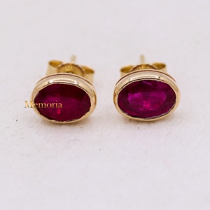Vente en gros de boucles d'oreilles à clous en or jaune 14 carats avec rubis ovales naturels sertis dans un cadre, Memoria Jewels - Product Image 1