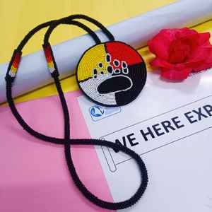 Collier artisanal avec pendentif patte d'ours perlé, sections jaunes, rouges, blanches et noires, et cordon long à suspendre sous la poitrine - Product Image 5