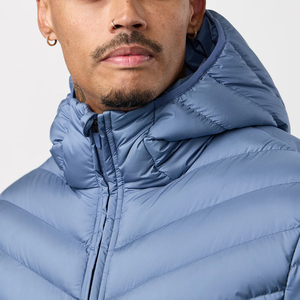 Veste universitaire bleue matelassée à capuche en toile, conçue pour le confort par temps froid, avec un modèle masculin confiant en sa tenue. - Product Image 5