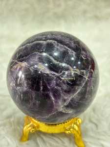 Esfera de cristal de amatista violeta con zonificación púrpura intensa, forma redonda pulida, subtil translucidez y característica mineral distintiva - Product Image 1