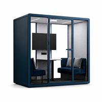 Pod lounge moderne bleu pour bureau, avec façade vitrée, sièges bleu marine, coussins gris clair et petite table