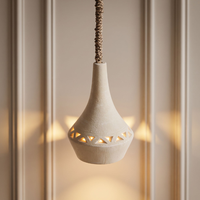 Le luminaire suspendu en céramique présente un design triangulaire simple et un élégant cordon en corde pour une lueur LED douillette près du lit.