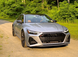Audi RS7 Sportback Coupé Argenté Vue Avant sur Route de Gravier avec Fond de Forêt Verte - Product Image 1