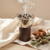 Brûleur d'encens en métal poli avec un grand bol rempli de charbons de bois incandescents, sur un support en bois, pour parfumer la maison.