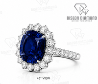 Magnifique bague halo en or blanc 18 carats avec pierre centrale bleu roi taille coussin, halo de diamants ronds et sangle fendue pavée brillante.