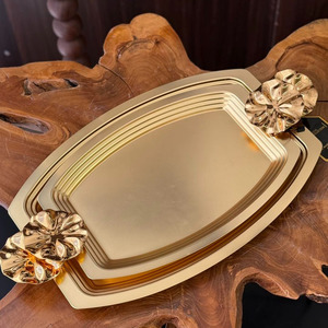 Ensemble de plateaux rectangulaires élégants en métal doré avec poignées décoratives en forme de fleurs pour un service chic et une présentation raffinée sur la table. - Product Image 1
