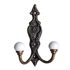 Gancho Doble de Hierro Fundido Estilo Victoriano con Puntas de Cerámica Blanca - Acabado Bronce Antiguo para Colgar Abrigos y Sombreros - Product Image 1
