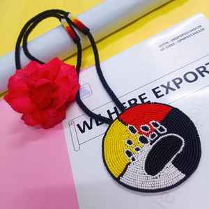 Collier artisanal avec pendentif patte d'ours perlé, sections jaunes, rouges, blanches et noires, et cordon long à suspendre sous la poitrine - Product Image 3