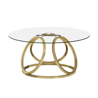 Table basse ronde en aluminium avec base en forme de feuille et plateau en verre transparent, finition dorée