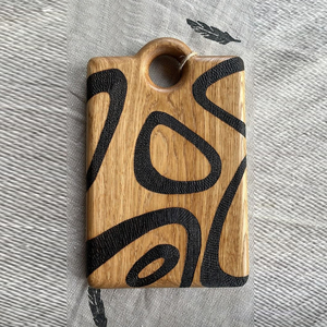 Planche à découper artisanale en bois de chêne avec des lignes tourbillonnantes noires texturées et audacieuses, trou de suspension supérieur, design artistique pour couper les légumes - Product Image 1