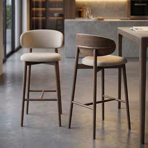 Chaise de bar surélevée en bois massif avec dossier arrondi et assise rembourrée douce, conçue pour une ambiance de repas chaleureuse et texturée - Product Image 1