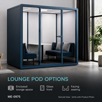 Pod lounge moderne bleu pour bureau, avec façade vitrée, sièges bleu marine, coussins gris clair et petite table