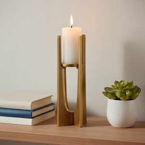 Porte-bougie en métal doré avec un design architectural, supportant une grande bougie blanche pour la décoration moderne de la maison - Product Image 1