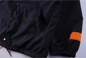 Veste coupe-vent noire pour homme avec accents de manches orange, ourlet rouge, cordon de serrage, boutons-pression, manches raglan et col rabattable - Product Image 2