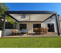 Pergola bioclimatique motorisée avec toit à lames orientables, structure en acier thermolaqué gris foncé et auvent à lames motorisées pour terrasse extérieure