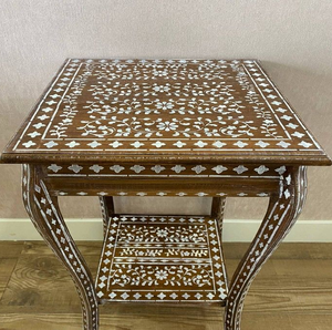 Mesa auxiliar cuadrada marrón con incrustaciones florales blancas y patas curvadas, y un estante inferior integrado. Disponible al por mayor. - Product Image 1