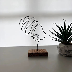 Escultura minimalista de rostro en alambre sobre base de madera, ideal para decoración de un rincón de lectura en el hogar y para combinar con libros como arte en la estantería. - Product Image 1