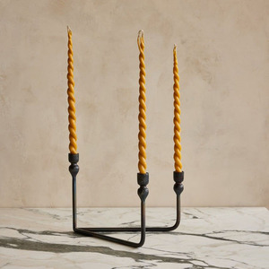 Candelabro triangular de metal bronce oscuro que sostiene tres velas cónicas de cera de abeja amarilla retorcida distintivas para una decoración elegante del hogar. - Product Image 1