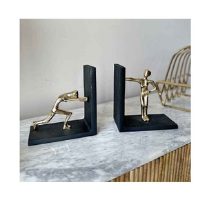 Figuras humanas minimalistas de oro que se aprietran contra los sujetalibros metálicos negros en forma de L, estilo moderno. Disponible a precios de mayorista. - Product Image 1