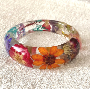 Chunky <b>clear</b> <b>resin</b> bangle filled with bright orange and pink dried garden flowers, available at wholesale prices. - Product Image 1