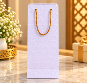 Sac cadeau en papier blanc gaufré fait main de qualité supérieure avec un élégant motif de feuilles en relief et des poignées en corde dorée pour un emballage cadeau de luxe - Product Image 1