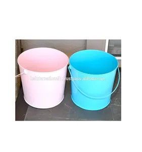 metal buckets for sale on wooden table outdoors. Many colorful decorative mini pails for garden flower plants stock